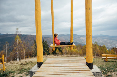 Boy in the mountains on a big swingの写真素材