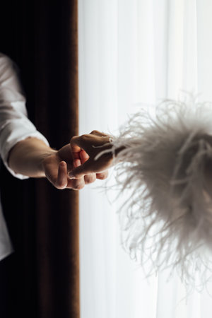 Female and male hands hold each other on a white background opposite the windowの写真素材