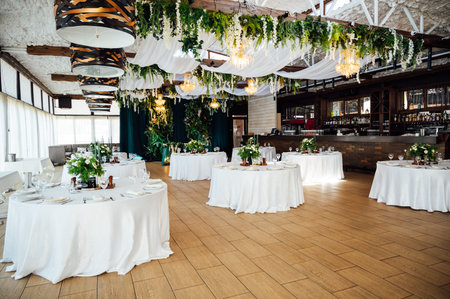 Luxurious restaurant. Luxurious interior, white tables, serving dishes and glasses for guests. Green decorの写真素材