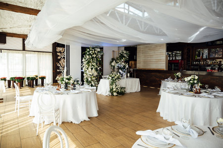 Luxurious restaurant. Luxurious interior, white tables, serving dishes and glasses for guestsの写真素材