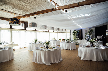 Luxurious restaurant. Luxurious interior, white tables, serving dishes and glasses for guestsの写真素材