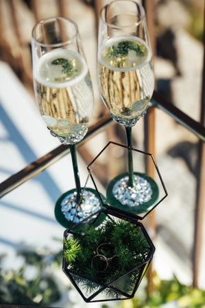 Two wedding glasses stand on a stand against the backdrop of the ceremony arch.の写真素材