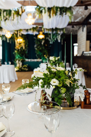 Luxurious restaurant. Luxurious interior, white tables, serving dishes and glasses for guests. Green decorの写真素材