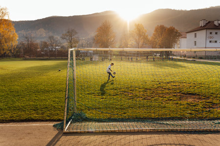 Young football player in white uniform posing on football field. School sports club.の写真素材