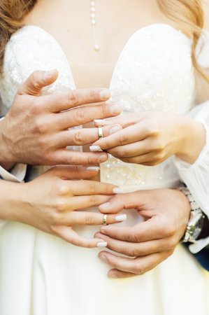 two gold wedding rings. the bride wears the groom wedding ring. newlyweds with rings on fingers.の写真素材