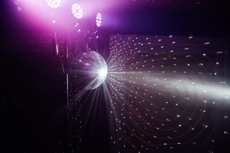 A mirrored disco ball reflects light rays throughout the room. Smoke enhances the visibilityの写真素材