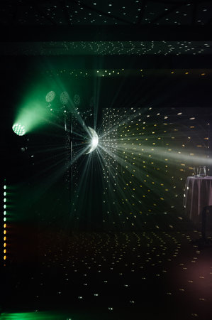 A mirrored disco ball reflects light rays throughout the room. Smoke enhances the visibilityの写真素材