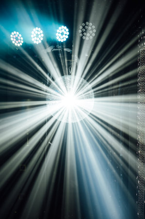 A mirrored disco ball reflects light rays throughout the room. Smoke enhances the visibilityの写真素材