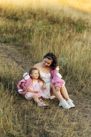 A young mother and daughter are hugging in nature among the mountains in beautiful identical sweatersの写真素材