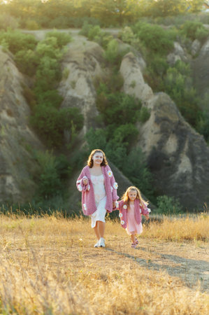 A young mother and daughter are walking in nature among the mountains in beautiful identical sweatersの写真素材