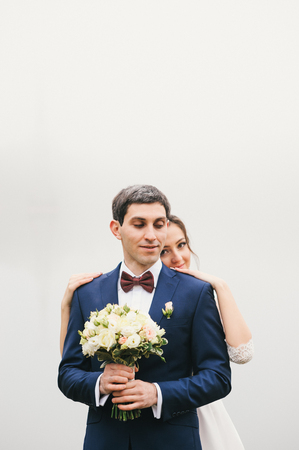 groom holds  bouquet and the bride behind his back put hands  on his shoulders  Valentine's Dayの写真素材