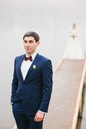 groom stands near  lake   bride standing on pierの写真素材