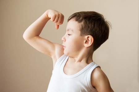 kid boy child showing muscles  fist strength trainingの写真素材