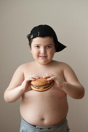 fat boy holding a hamburger and smilingの写真素材