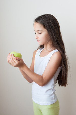 Girl in shirt holding three green appleの写真素材