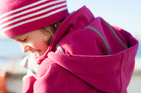little girl in a coat on which a ladybug sittingの写真素材