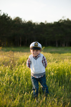 Boy in captain's hat standing in front of the forestの写真素材