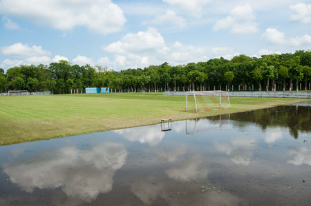 green football field flooded with rain waterの写真素材