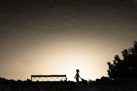 little boy, bench and tree reflected in the pondの写真素材