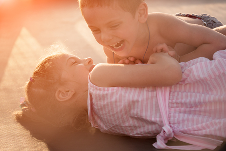 happy boy and girl playing lying on a trampolineの写真素材