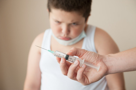 syringe before sad fat boy who fear injectionsの写真素材