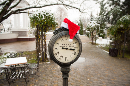 stylish vintage clock with santa hat and the words Merry Christmas