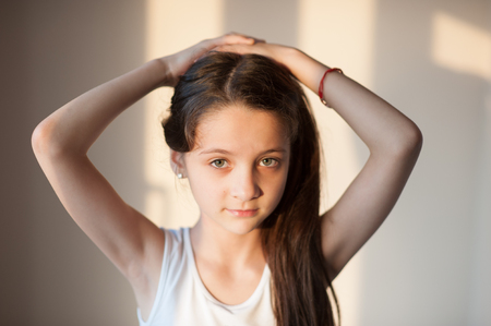 adorable young girl doing her hair with both handsの写真素材
