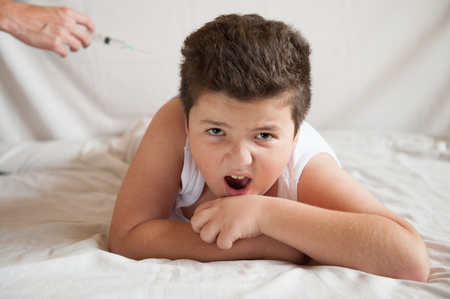 scared fat boy is afraid of the hand with a syringe and screamsの写真素材