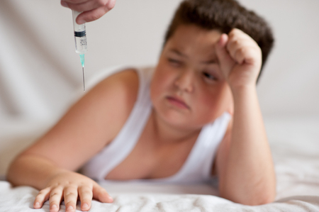 scared little fat boy grabbed his head, frightened by the hand with a syringeの写真素材