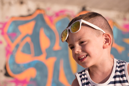 cute smiling small boy in trendy sunglasses on graffiti backgroundの写真素材