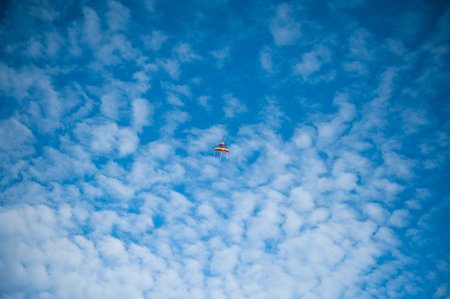 beautiful colorful kite flying in a blue cloudy skyの写真素材