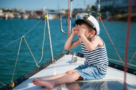 Funny little boy captain on a yacht in the summerの写真素材