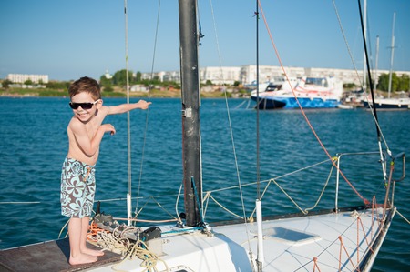 happy little kid wearing shorts and sunglasses aboard luxury yachtの写真素材