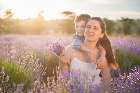 happy beautiful mother and child on the lavender field at sunsetの写真素材
