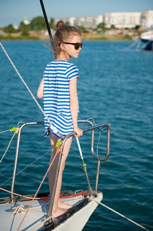 fashionable little kid aboard luxury boat in summer sea cruiseの写真素材