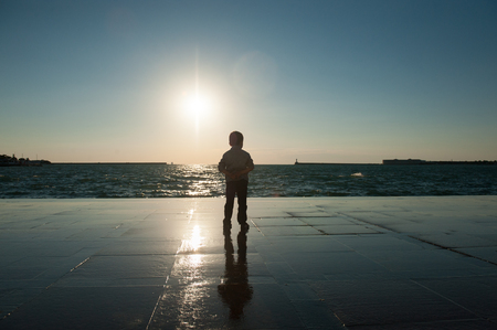 one little boy watching the sea against the sunsetの写真素材