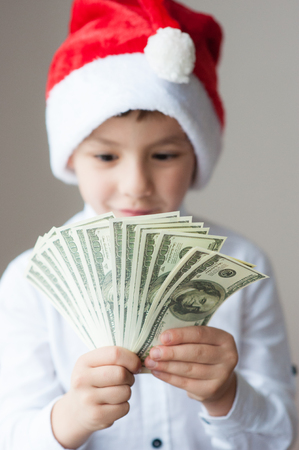 happy kid in Santa hat holding hundred-dollar bills packの写真素材