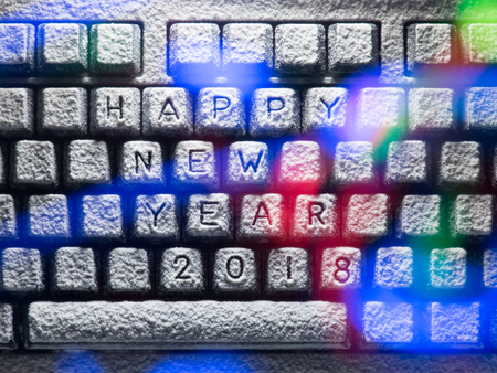 keyboard covered with snow with title happy new year 2018 lit by colorful lightsの写真素材