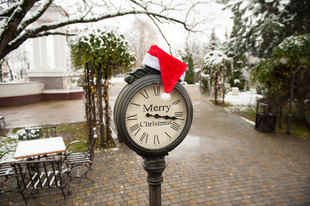 vintage street clock with the inscription Merry Christmas and Santa Claus hat on them outdoorの写真素材