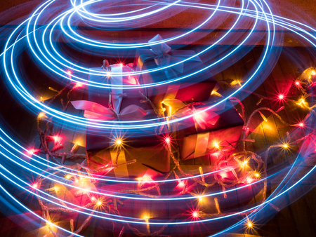 boxes with Christmas gifts with garlands with christmas lights with star effect and circular traces from painting by lightの写真素材