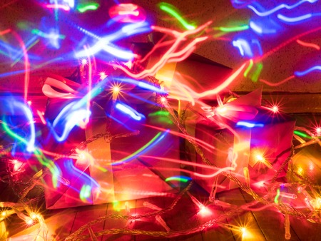 boxes with Christmas gifts with garlands with bulbs and traces from drawing by light
