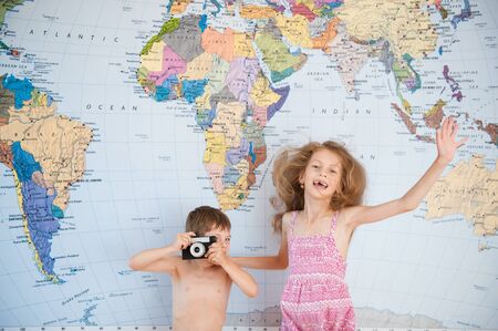 two kids having fun on the background of map of the worldの写真素材