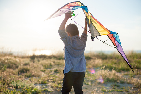dreamy little boy with big kite in his hands over his headの写真素材