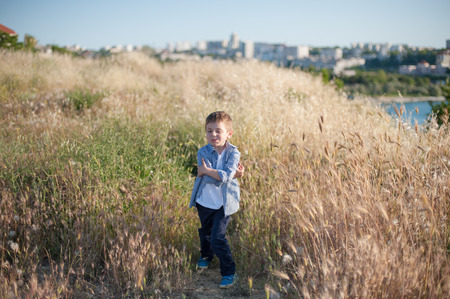 funny cute little boy grimacing standing in the middle of a field of plantsの写真素材