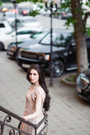 beautiful pretty girl in summer dress on background of city streets with expensive cars and green treesの写真素材
