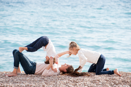 happy family consisting of beautiful mother and two cute children playing by seaの写真素材