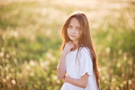 portrait of beautiful young girl in summer sunset fieldの写真素材