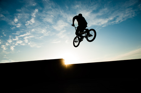 silhouette of jumping biker on summer sunset with copy space