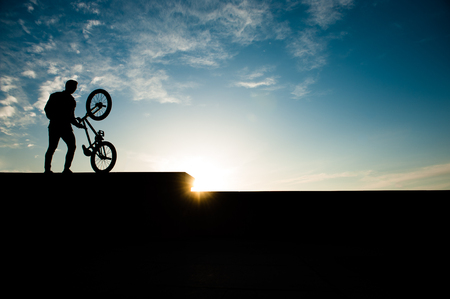 silhouette of healthy young man with bicycle on summer sunser background outdoor activityの写真素材