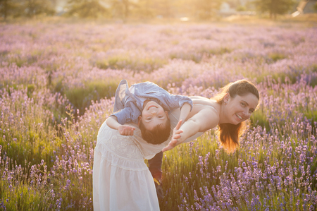 happy beautiful caucasian family mother child in lavender flower field in summer sunsetの写真素材